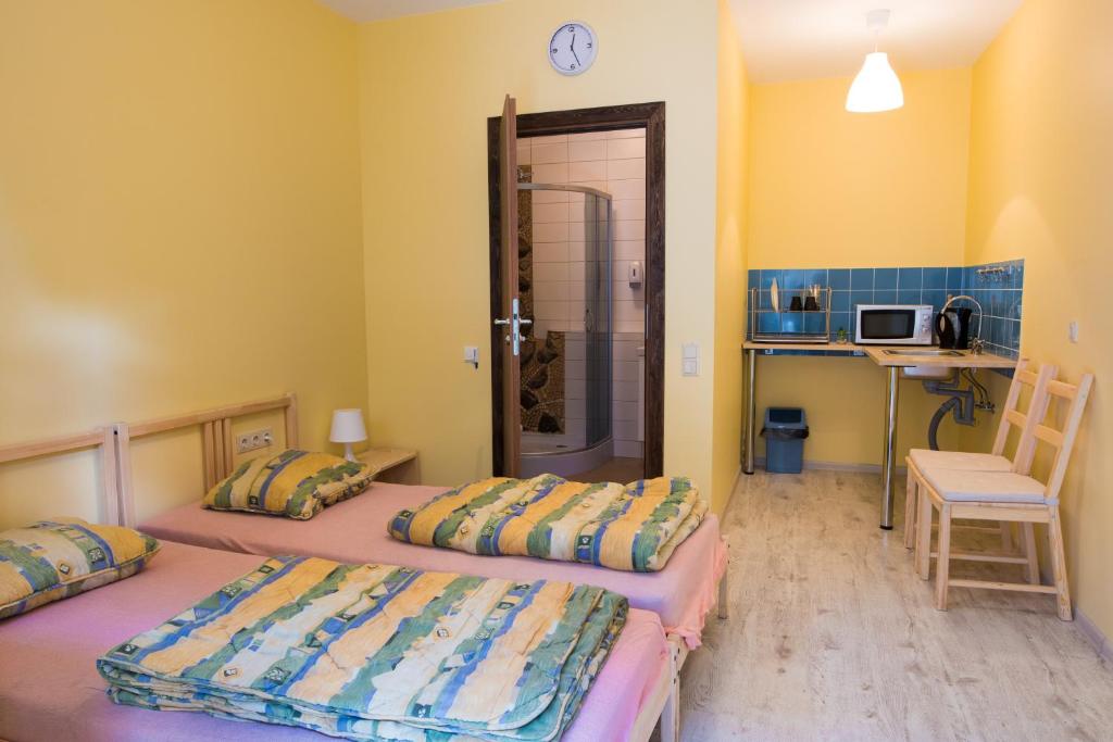 2 camas en una habitación con paredes amarillas en Fortuna Hostel, en Vilna
