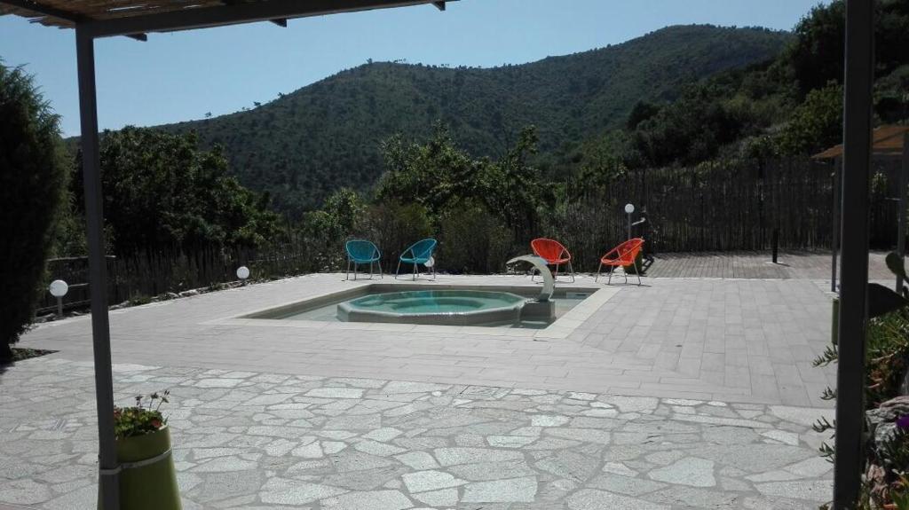 three chairs and a swimming pool with mountains in the background at Oroverde in Bergeggi
