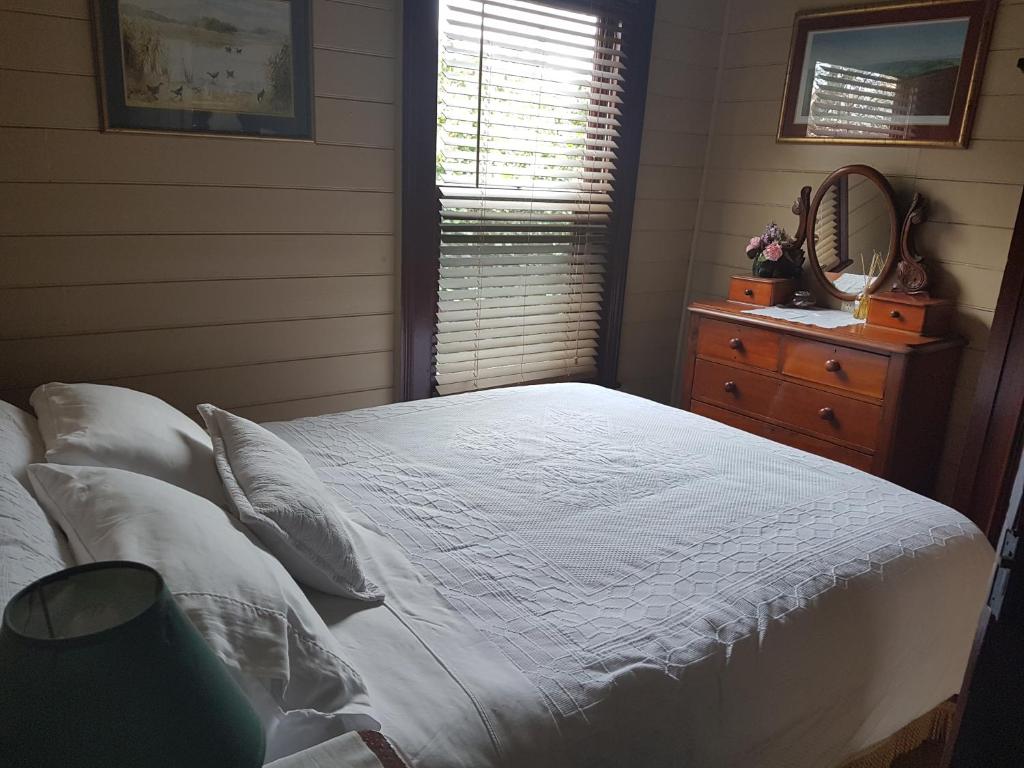 a bedroom with a white bed and a window at Twomey's Cottage in Queenscliff