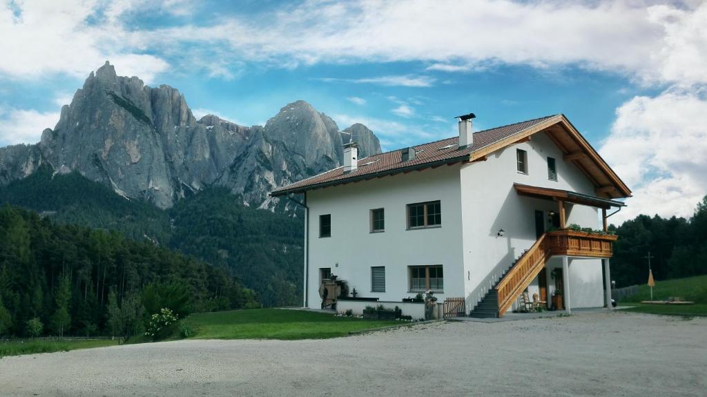 a white house with mountains in the background at Parlunkhof in Castelrotto