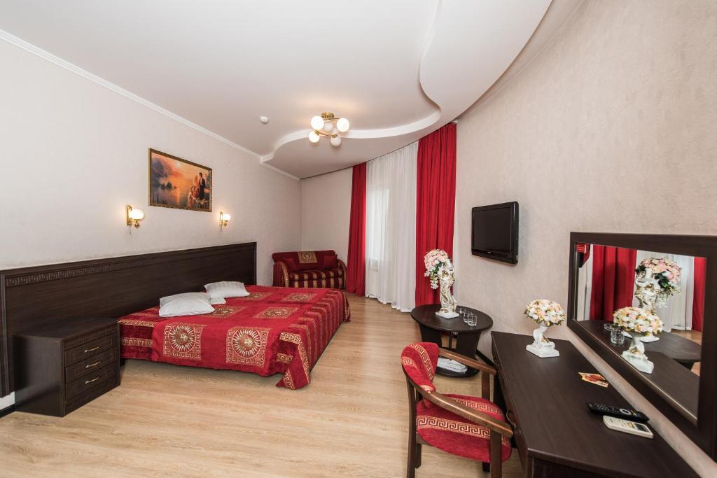 ノヴォロシースクにあるПарадизの赤いベッドとデスクが備わるホテルルームです。