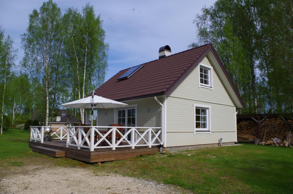 Casa blanca con terraza con sombrilla en Ööbiku Holiday House, en Antsla