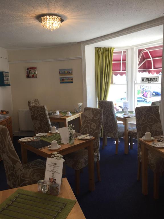 una sala da pranzo con tavoli, sedie e una finestra di The Beach House a Weymouth