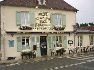 a hotel with tables and chairs in front of a building at Logis hotel Saint-Joseph in Sancoins