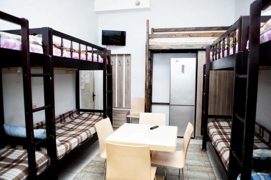 モスクワにあるХостел Вежливый Лось на Сходненскойの二段ベッド、テーブル、椅子が備わる客室です。