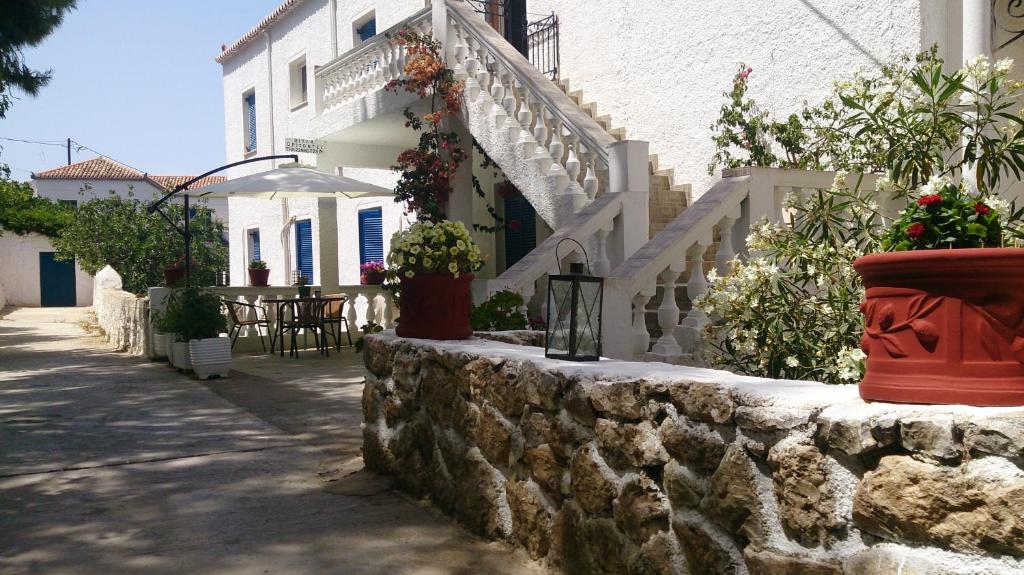 uma parede de pedra com vasos de flores e uma mesa em frente a um edifício em Villa Orizontes em Spetses