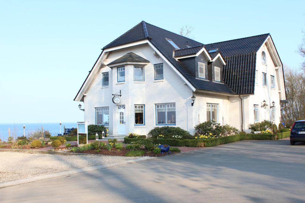 a large white house with a black roof at Waldpavillon in Fehmarn