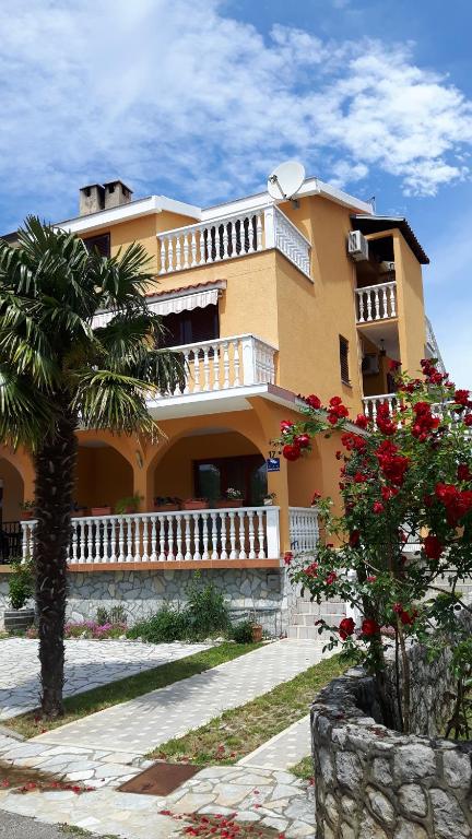 a large yellow house with a palm tree in front of it at Apartment Krizanovic in Malinska