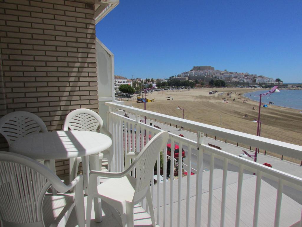 a balcony with a table and chairs and a beach at Apartamentos Forner in Peniscola