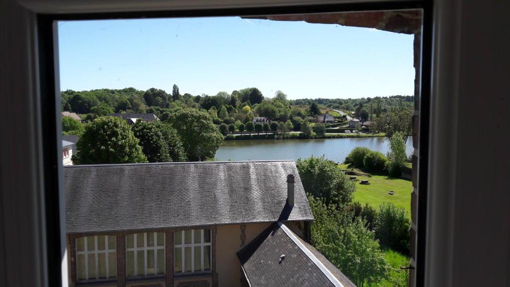 Blick auf ein Haus und einen See aus dem Fenster in der Unterkunft Le refuge de l'abbaye in Saint-Évroult-Notre-Dame-du-Bois