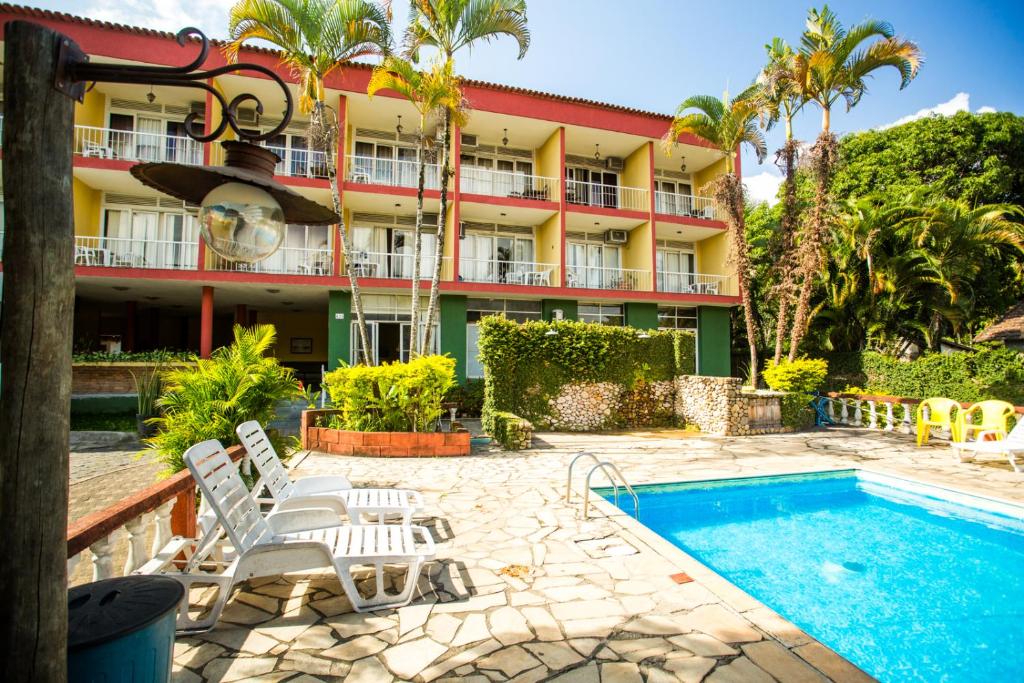 um hotel com piscina em frente a um edifício em Hotel Pelicano em Ilhabela