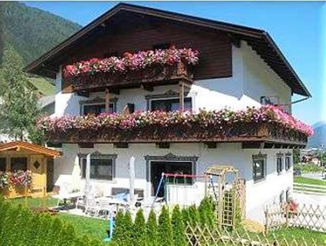 a white house with flowers on the top of it at Pension Kristall in Neustift im Stubaital
