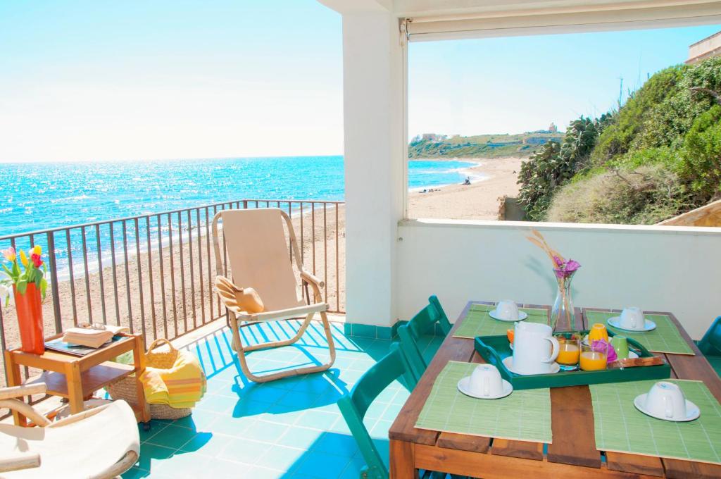 einen Balkon mit einem Tisch und Stühlen sowie einem Strand in der Unterkunft Le Terrazze di Apollo - Case Tilotta in Marinella di Selinunte