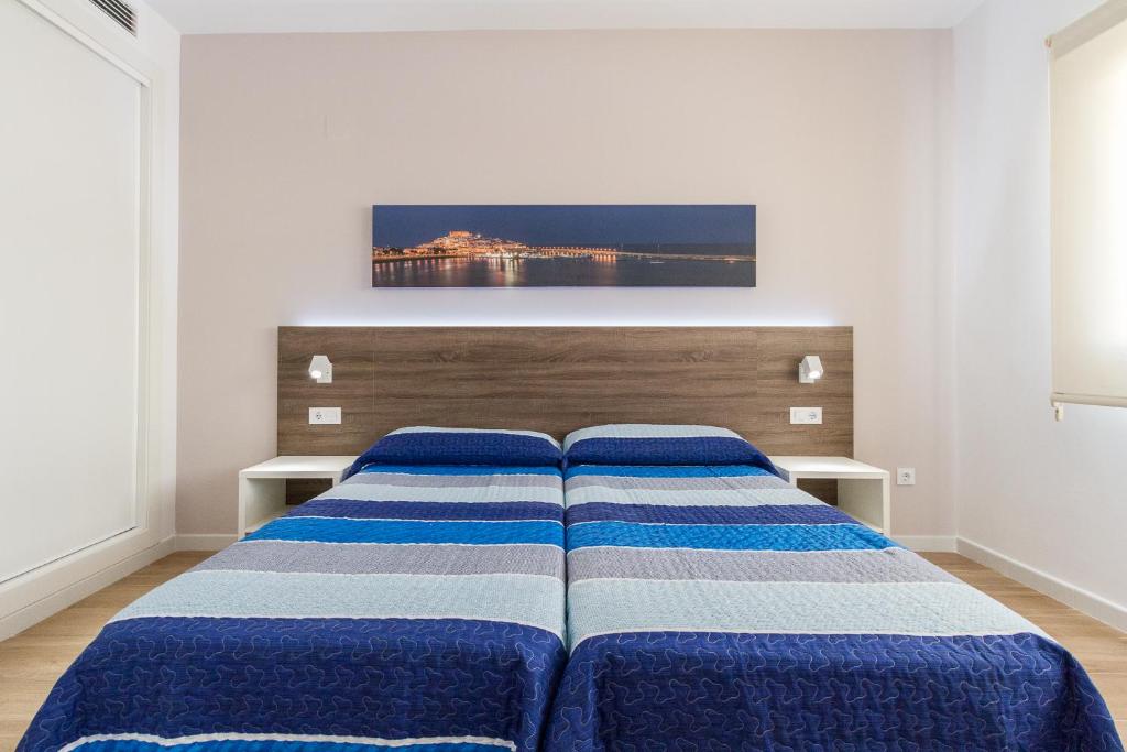 a bedroom with a bed with blue and white sheets at Iberflat Apartamentos Marynton in Benicarló