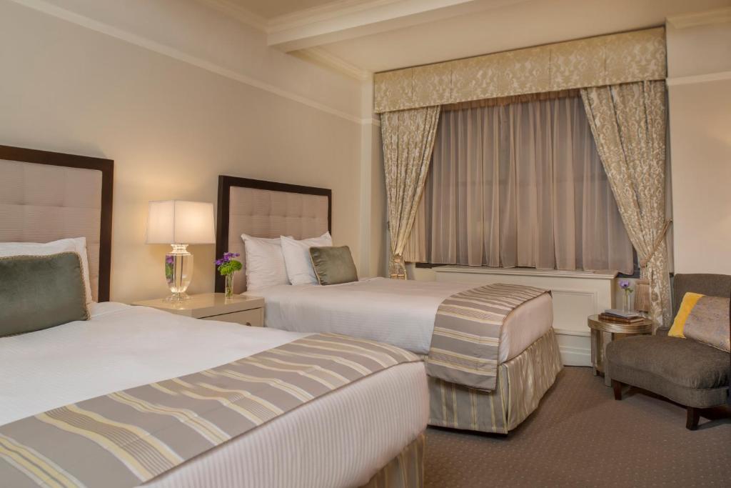 a hotel room with two beds and a chair at Warwick New York in New York