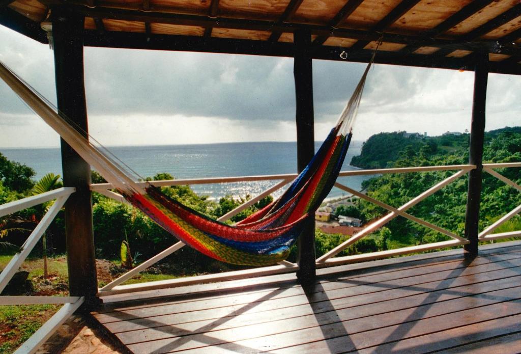 a hammock on a deck with a view of the ocean at I VIEW - in Long Bay in Port Antonio