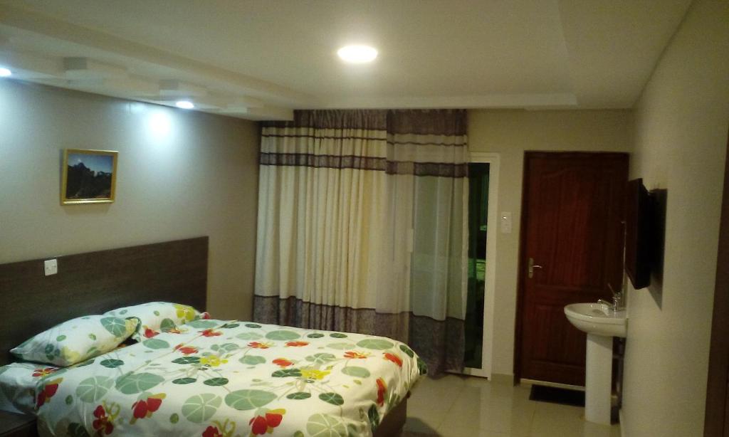 een slaapkamer met een bed, een wastafel en een toilet bij Adala Motel in Meru
