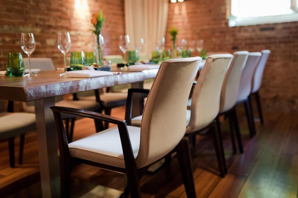 una mesa larga con sillas blancas y copas de vino en Hotel Navigare, en Buxtehude