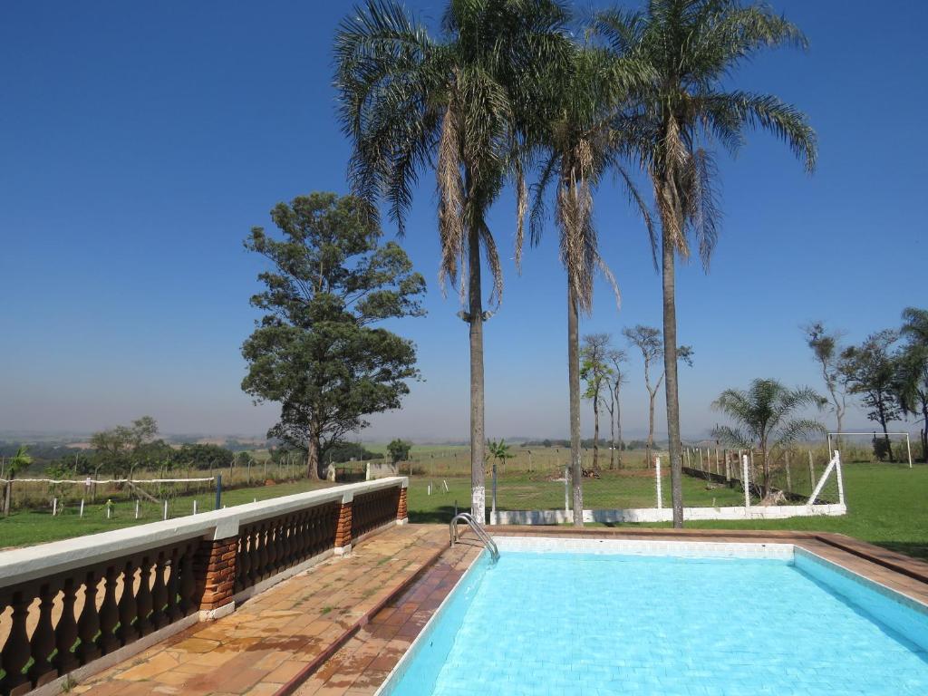 une piscine avec des palmiers en arrière-plan dans l'établissement Chacara Samambaia, à Piracicaba