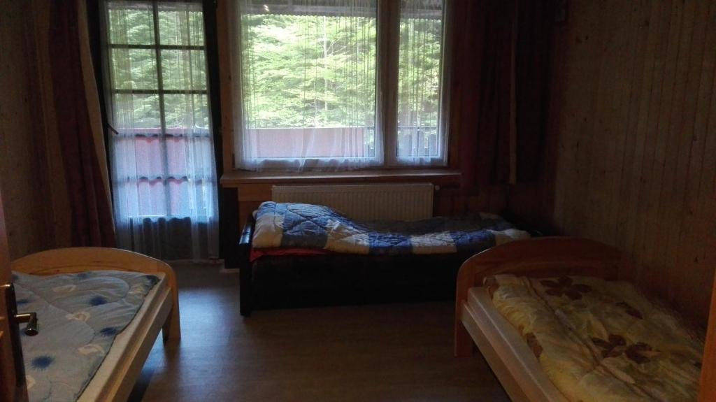 two beds in a room with two windows at Agroturystyka pod Pstragiem in Zawoja