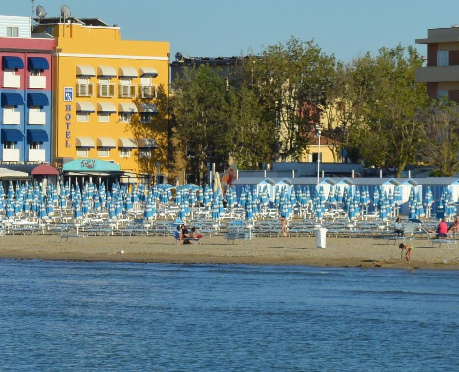 uma praia com cadeiras e guarda-sóis junto à água em Hotel Amelia em Fano