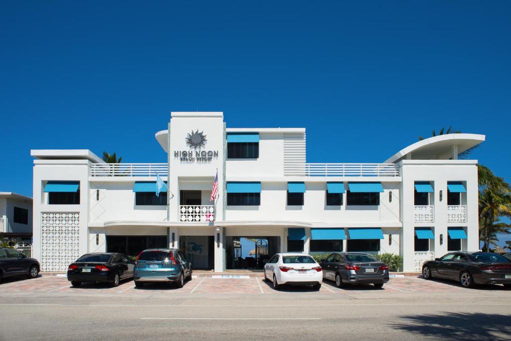 a white building with cars parked in a parking lot at High Noon Beach Resort in Fort Lauderdale