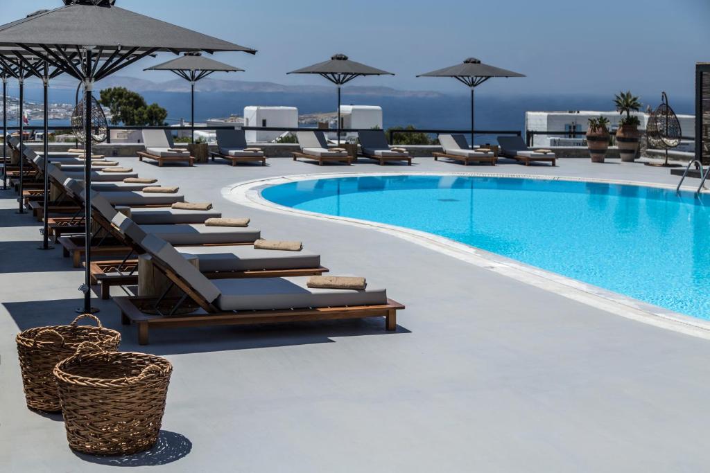 a large swimming pool with lounge chairs and umbrellas at My Mykonos Hotel in Mýkonos City