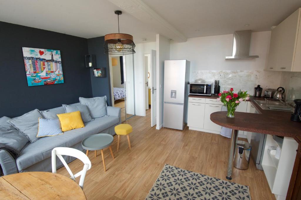 a living room with a blue couch and a kitchen at Le Petit Nid d'Honfleur in Honfleur