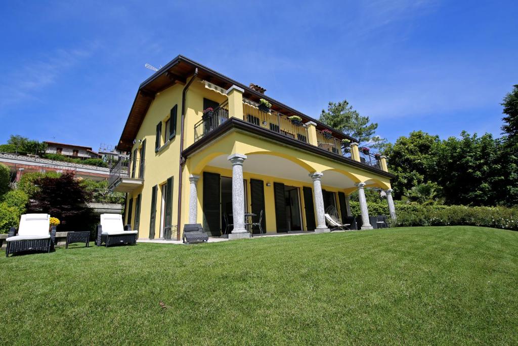 een groot geel huis met stoelen op een gazon bij Casa Ketty in Bellagio