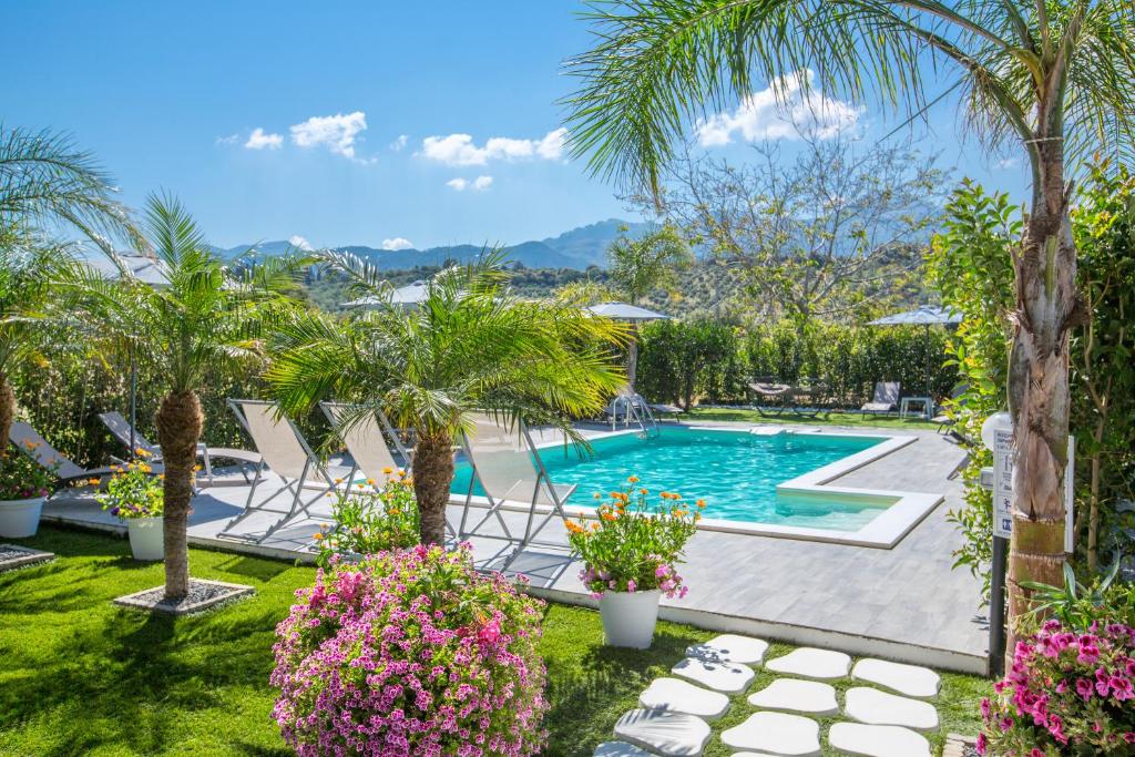 una piscina en un patio con palmeras y flores en Le Zagare, en Lascari