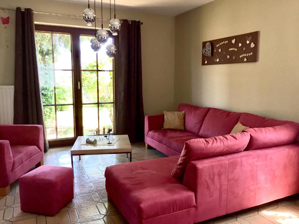 a living room with a red couch and a table at Le Valdine in Jemeppe