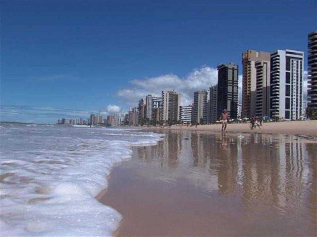 ein Strand mit Gebäuden und Menschen, die am Strand spazieren in der Unterkunft Studio 51 residence in Recife