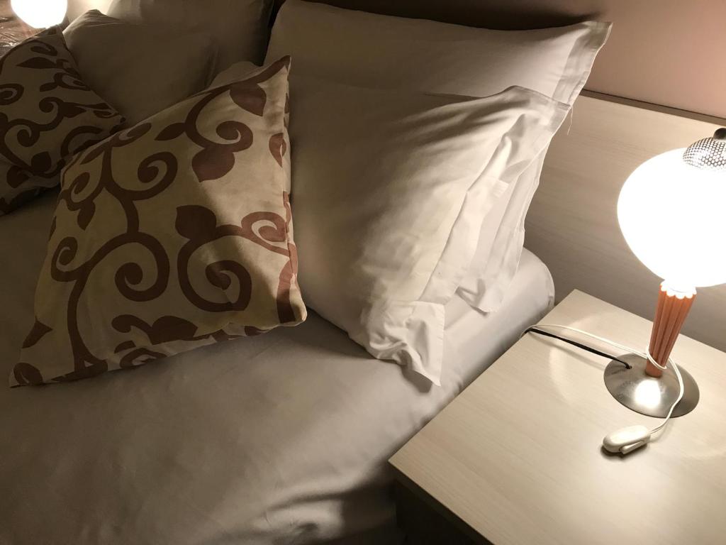 ein Bett mit zwei Kissen und einer Lampe auf einem Tisch in der Unterkunft Papali in Catania