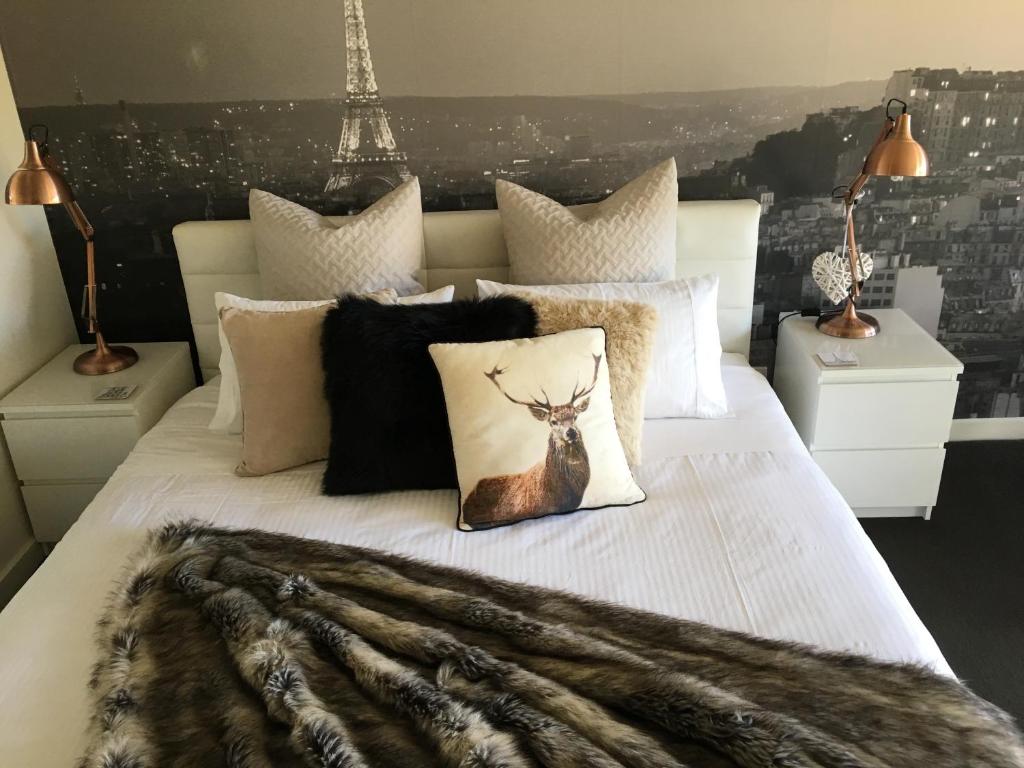 a bedroom with a white bed with a blanket and the eiffel tower at Paris Lorne in Lorne