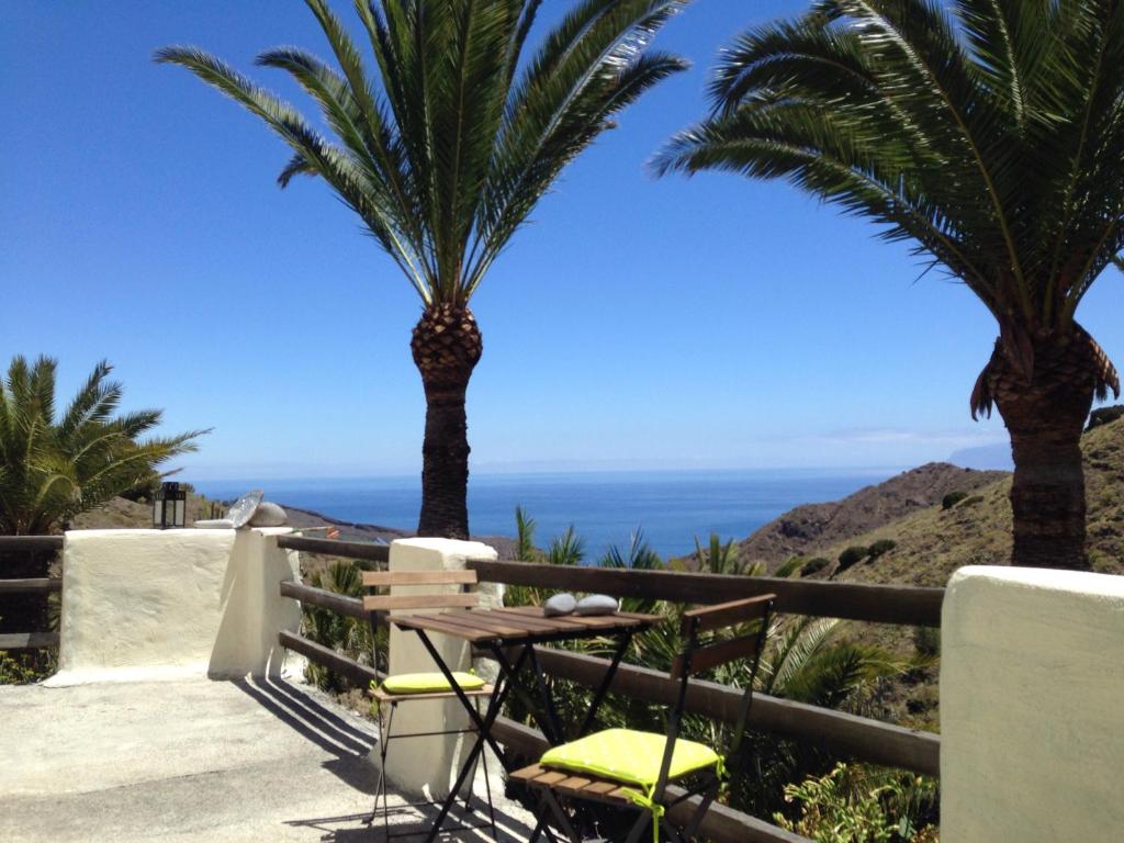 einen Tisch und Stühle auf einem Balkon mit Palmen in der Unterkunft Casa Aloha in Hermigua