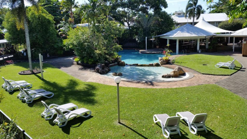 Cairns Gateway Resort في كيرنز: حديقه خلفيه بها مسبح وبه كراسي ومسبح