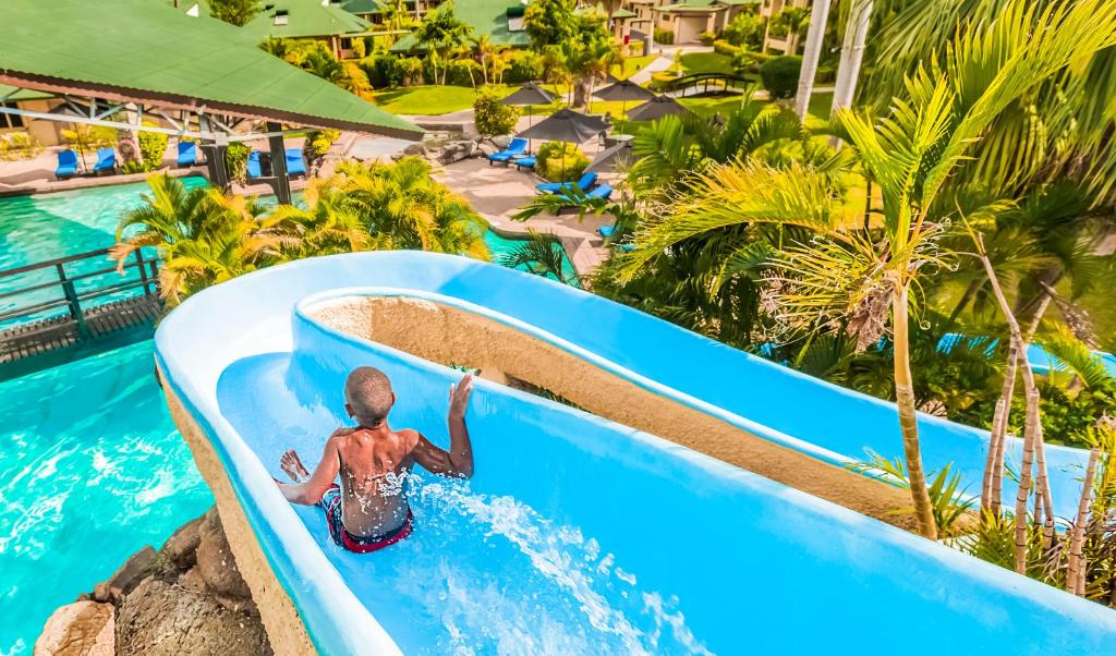 un joven montando un tobogán de agua en un complejo en Tokatoka Resort Hotel, en Nadi