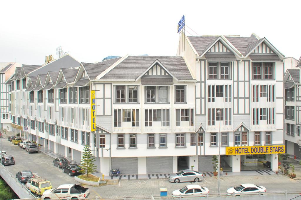 um grande edifício branco com carros estacionados num parque de estacionamento em Hotel Double Stars Cameron Highlands em Cameron Highlands