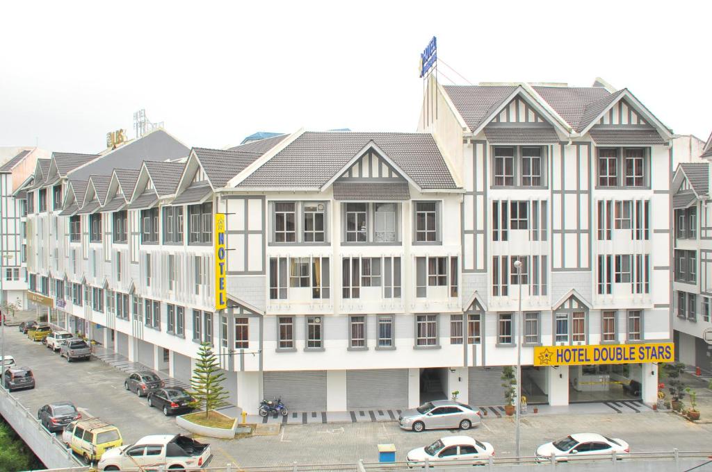 a large white building with cars parked in a parking lot at Hotel Double Stars Cameron Highlands in Cameron Highlands