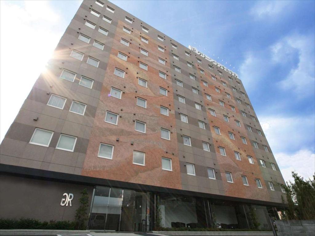 un edificio de ladrillo alto con el sol brillando en él en Green Rich Hotel Tosu Ekimae en Tosu