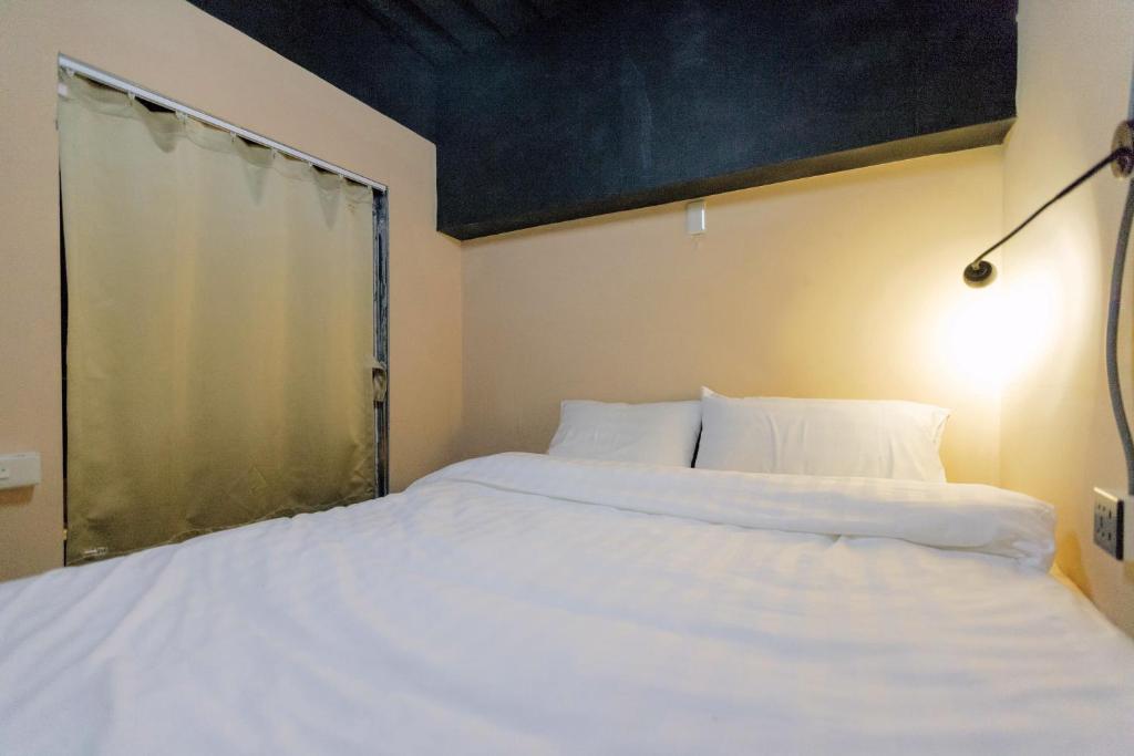 a bedroom with a large white bed with a window at Angels Hostel Taipei Ximen in Taipei