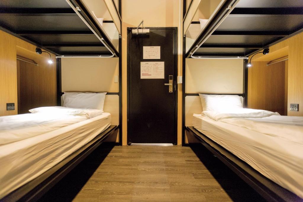 two bunk beds in a room with a door at Angels Hostel Taipei Ximen in Taipei