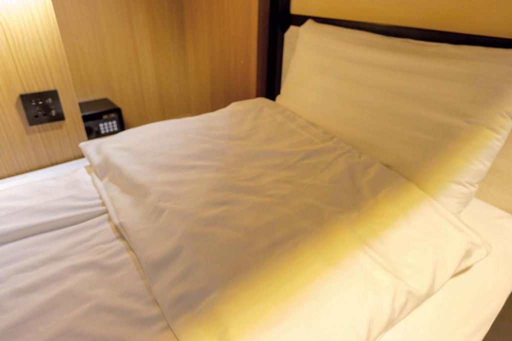 a white bed with a pillow on top of it at Angels Hostel Taipei Ximen in Taipei