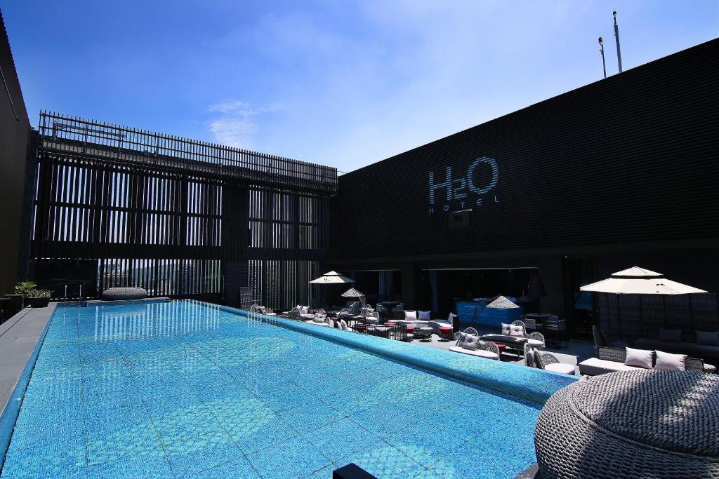 a swimming pool with chairs and umbrellas next to a building at H2O HOTEL in Kaohsiung
