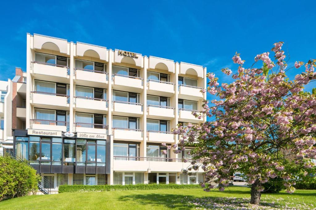 um edifício com uma árvore florida à sua frente em Villa am Meer em Grömitz