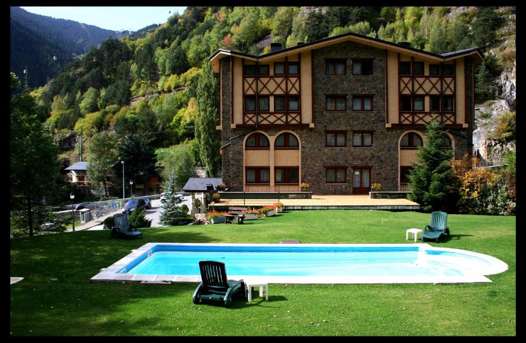 a large building with a swimming pool in the grass at Hotel Xalet Verdú in Arinsal