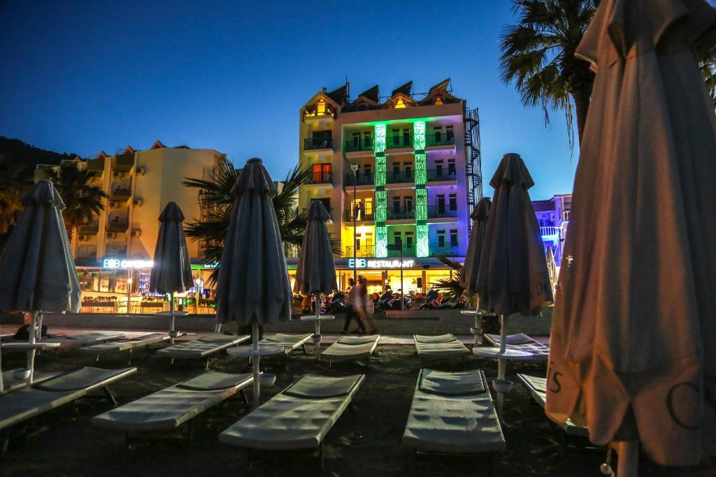 a group of lounge chairs with umbrellas in front of a building at B&B Yuzbasi Beach in Marmaris