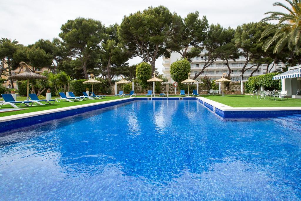 una gran piscina con sillas y sombrillas azules en Hotel Foners en Playa de Palma
