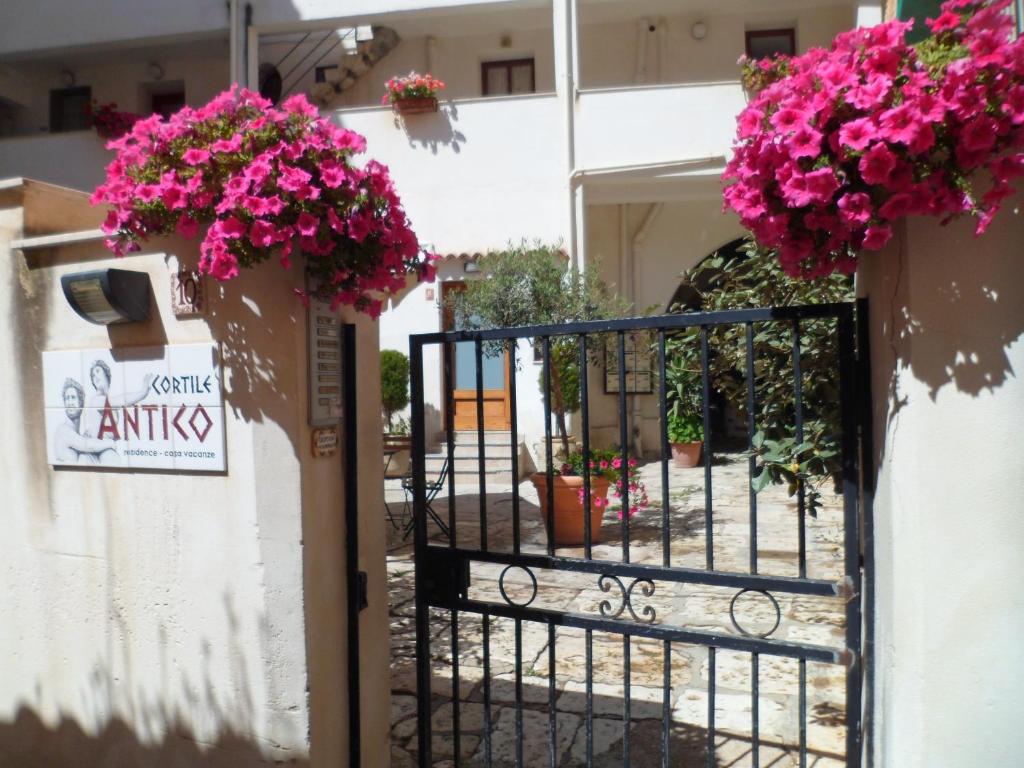 un cancello per una casa con fiori rosa sopra di Cortile Antico a Trapani