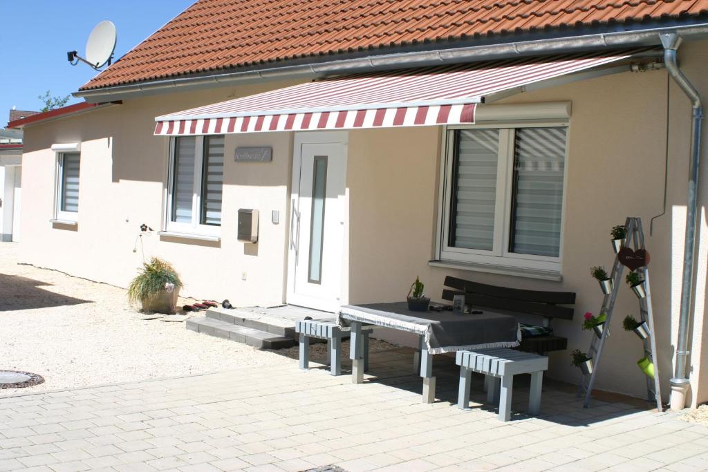 een huis met een picknicktafel en banken ervoor bij Ferienwohnung mit Herz für Tiere in Kaufbeuren